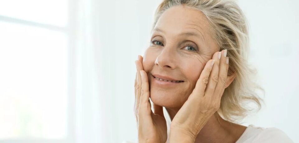 como-estimular-a-producao-de-colageno Mulher com mãos no rosto sorrindo